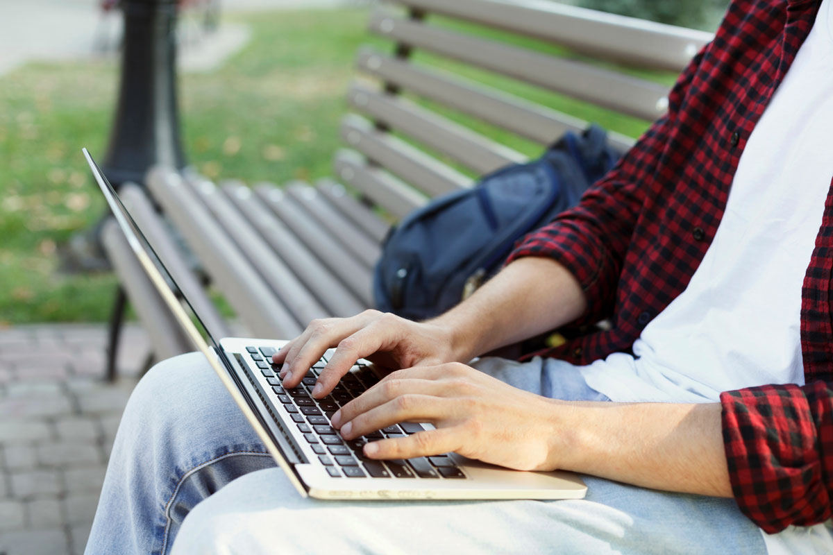 Man connecting laptop to outdoor wifi network